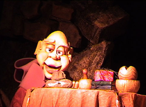 Portrait de la marionnette Dalfis devant sa table et ses accessoires de magie. Scène du spectacle pour enfants : L'Etrange Noël.