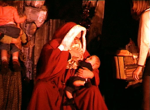 Le Père Noël avec un bébé dans les bras dans un spectacle de Noel pour enfants